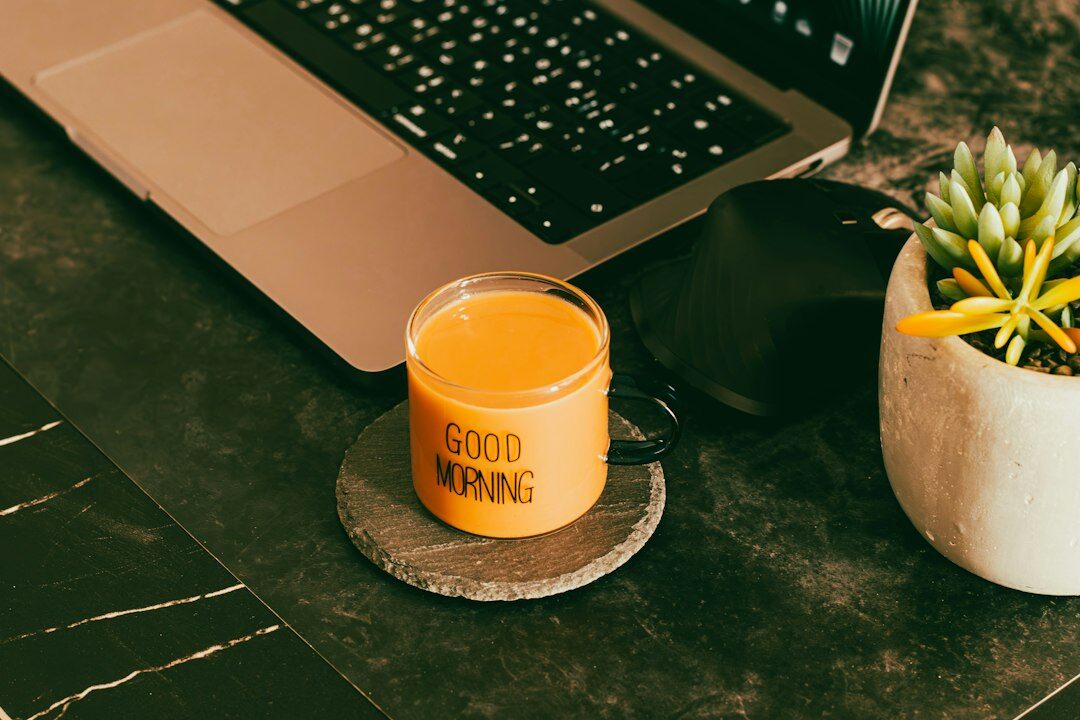 Video editor typing on a laptop next to a notebook and coffee